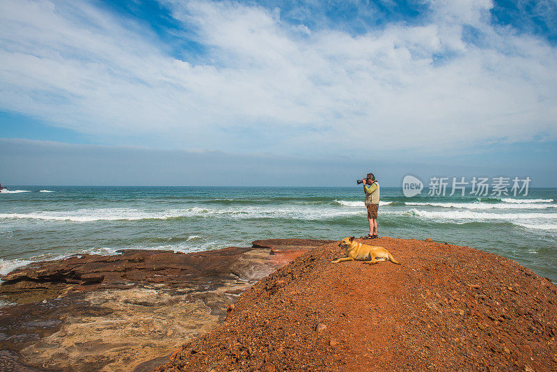 高级摄影师和橙色狗在大西洋海岸，Legzira, Sidi Ifni，摩洛哥，北非